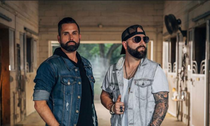 Country music duo, Chris James Band, standing in a stable. 