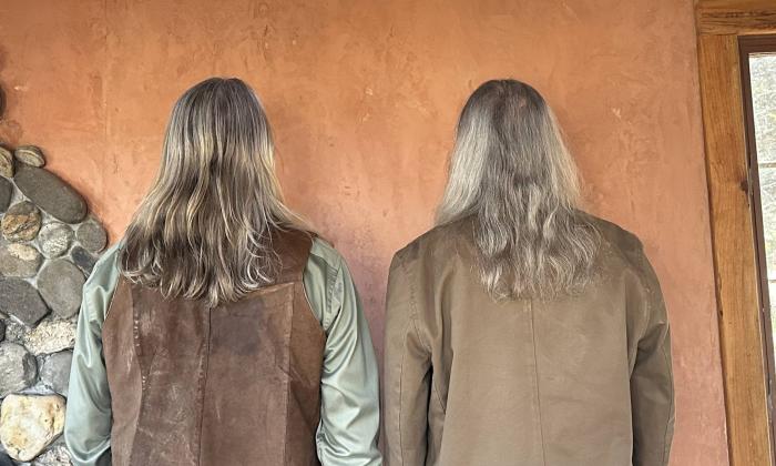 Bandmates from the Sounds of Simon & Garfunkel Tribute Band pose against a tan wall.