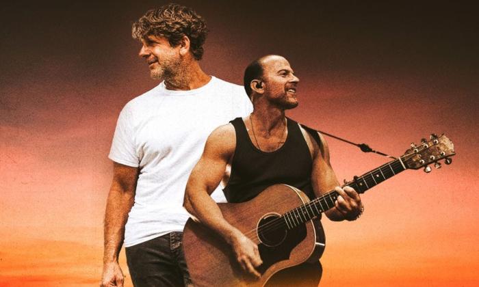 Billy Currington and Kip Moore smile and pose in front of a black and brown backdrop.