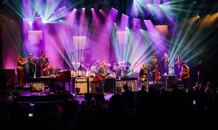 Bandmates from Tedeschi Trucks perform in front of a large audience.