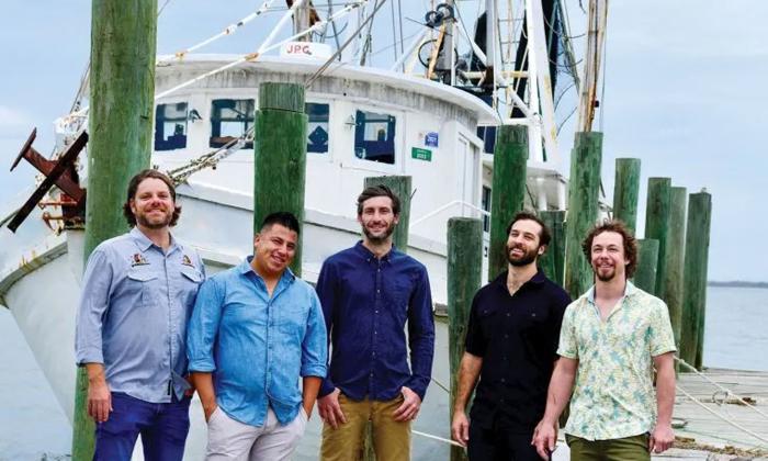 The band Gilberto '77 standing infront of a shrimp boat in Fernandina Beach, Florida