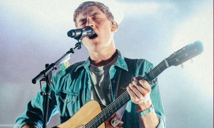 Sam Barber sings while strumming his guitar.