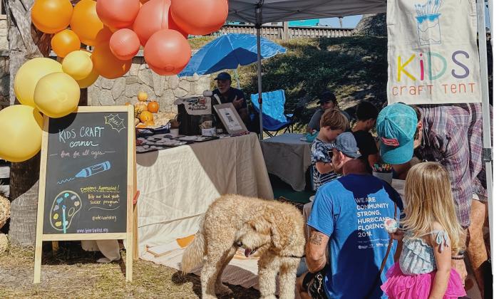 A kids craft tent, with parents, kids, and dogs enjoying the fun