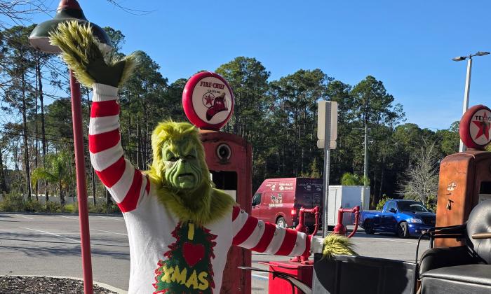 The Grinch on the grounds of the Classic Car Museum waving