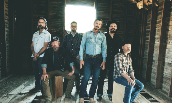 Bandmates from Turnpike Troubadours pose in a room with exposed wood on the walls and floor.