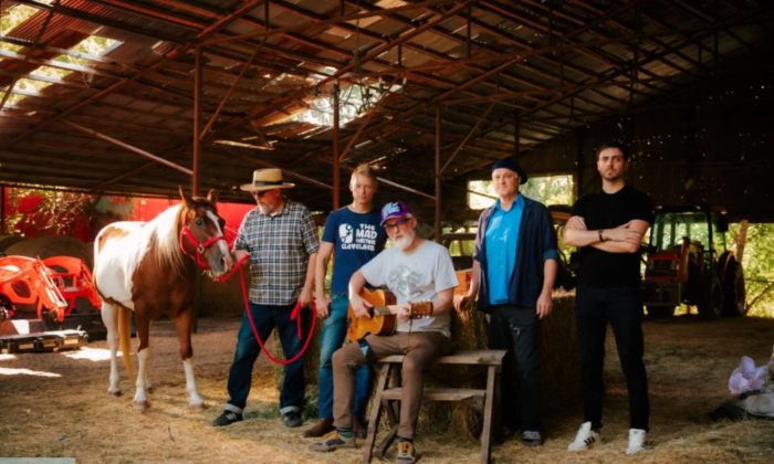 Bandmates from Cake smile and pose in a barn.