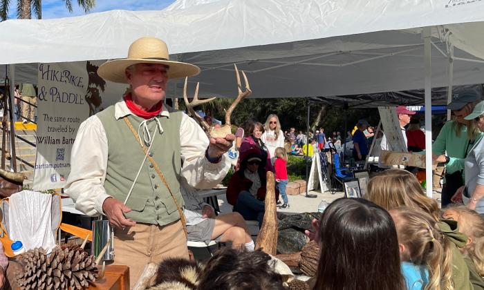 A man portraying William Bartram holding a deer skull while talking with children