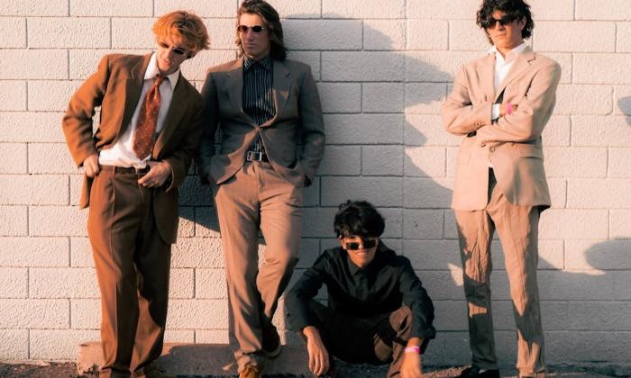 Bandmates from Foxtide pose in front of a brick wall.