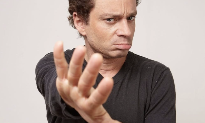 Chris Kattan poses in front of a white backdrop.