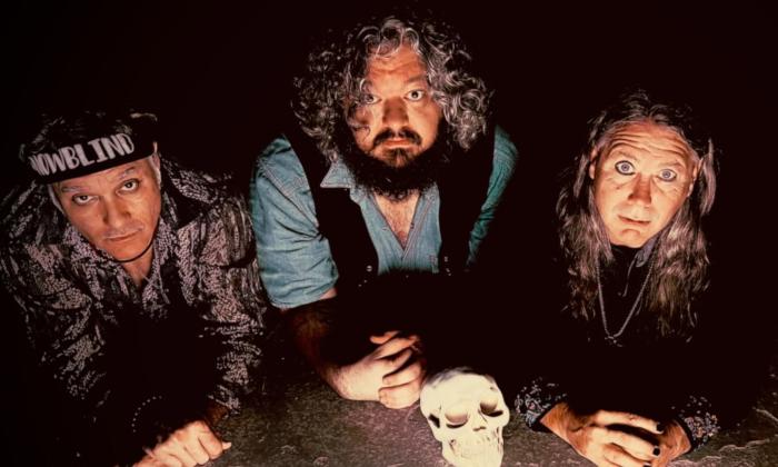 Bandmates from Snowblind pose in front of a human skull.
