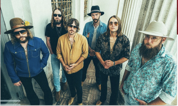 Bandmates from Whiskey Myers pose while using a white building with pillars as their backdrop.