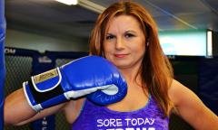 A woman places her boxing gloves to her chin. 