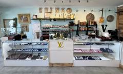 The counter of a store and pawnshop with coins, a guitar, and jewelry in cabinets