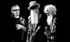 Bandmates from ZZ Top pose in front of a black backdrop.