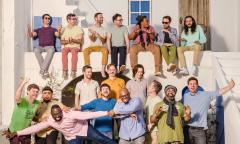 Three rows of band members arranged along a balcony, relaxed in casual clothes