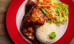 A quarter rotisserie chicken with white rice and a salad