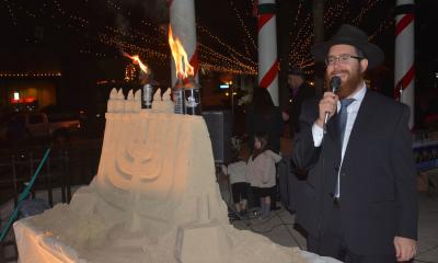 Rabbi Vogel speaks after lighting the sand sculpture Menorah