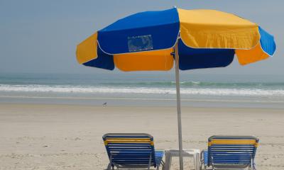 A blue and gold beach umbrella standing over two matching chairs 