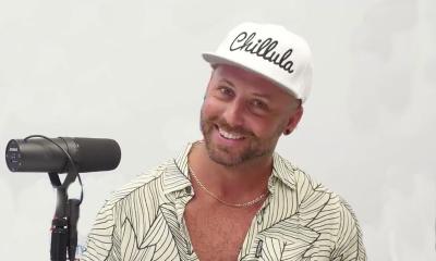 Musician Chase Rideman with a microphone, smiling, in baseball cap