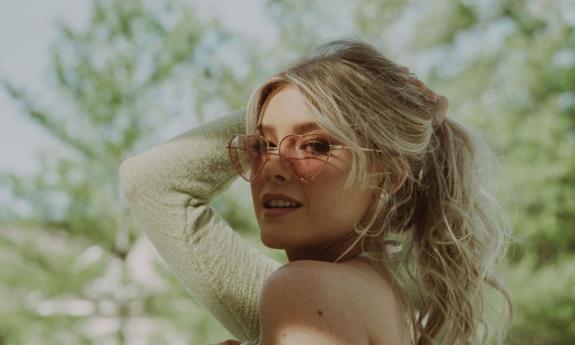 Country singer and songwriter Emily Brooke wearing sunglasses with trees behind her