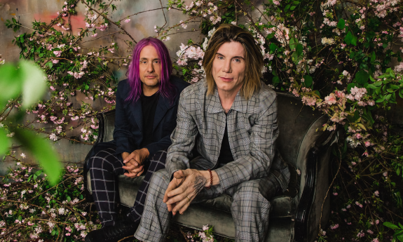 The alternative rock band the Goo Goo Dolls sit near a colorful flower backdrop. 