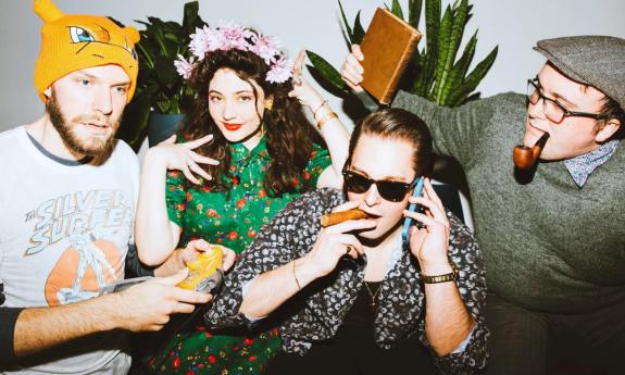  Tatiana Eve-Marie and Avalon Jazz Band pose with colorful clothing while standing in front of a group of plants 