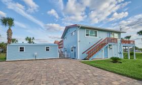 A blue house with a large paved driveway, offers two vacation rental apartments as part of OceanView Lodge in Vilano