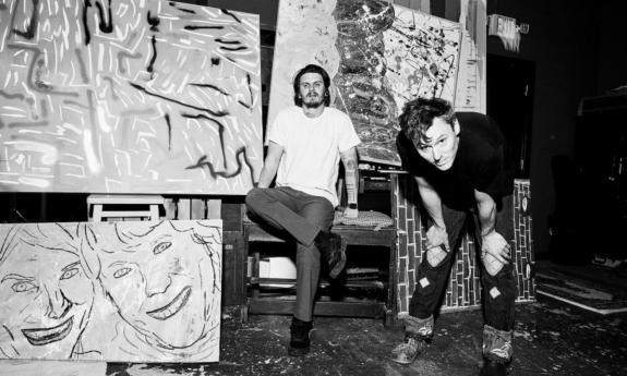 The Front Bottoms pose on stage with abstract art.