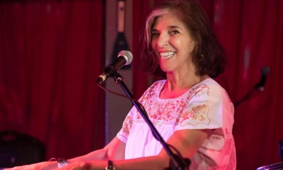 Marcia Ball smiles and plays a keyboard on stage. 