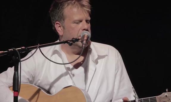 Wendell Mobley singing at a microphone with his guitar