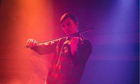 Christian Ward playing his fiddle under blue and orange stage lights