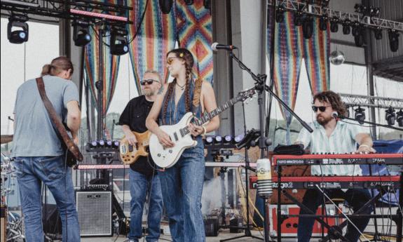 The band Magnolia Boulevard performs on stage using guitars and a keyboard. 