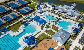An aerial view of a recreational complex with pools, tennis courts, and a clubhouse