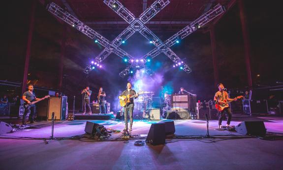 Bandmates from O.A.R. perform on stage while holding their guitars. 