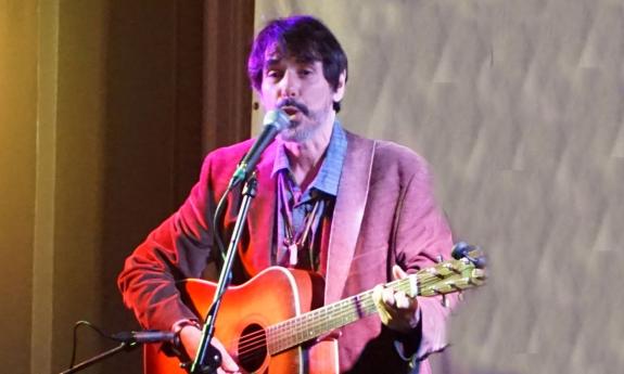 Singer-songwriter Spook Handy onstage playing guitar and singing