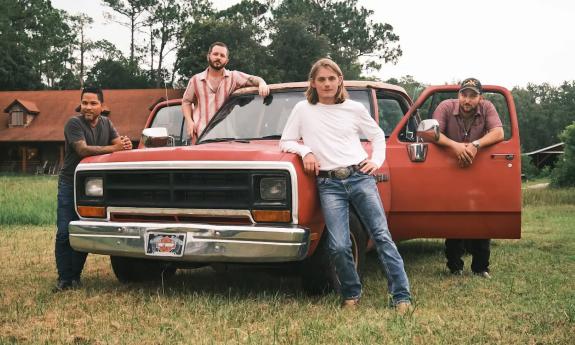 Members of the Chase Ryland Band posing in front of a classic pickup truck