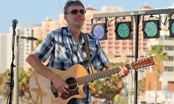 Greg Culp clutches his guitar while performing on stage. 