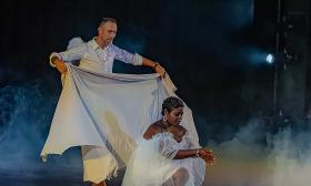 Two dancers in white, pose before the start of their performance