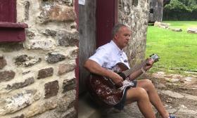 Mike Metterhouse sitting and playing the guitar