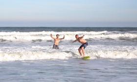 A surf instructor cheering on his student