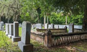 This old section of a cemetery includes a family plot surrounded by a low cast concrete fence