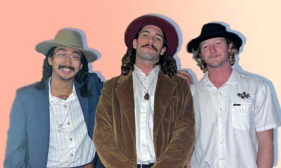 Three musicians smile for the camera in trendy suede suits and hats. Pastel gradient BG.