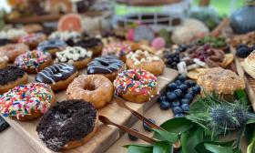 A selection of donuts and fruit, accented by greenery