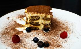 A plate of tiramisu with fruit and additional garnishes