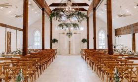 A wedding ceremony with greenery accents in the light fixtures