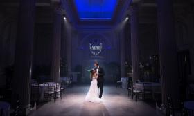 A bride and groom spotlit in venue with dark blue lighting