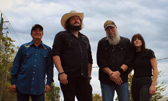 The band Whalin, four members wearing dark shirts and standing on a road