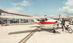 A small private plane, white with red stripes, sitting on the tarmac during a show