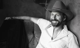 Country artist, Brett Sheroky, posing in a cowboy hat on a couch