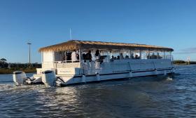 A passenger pontoon boat gliding past the large cross in St. Augustine